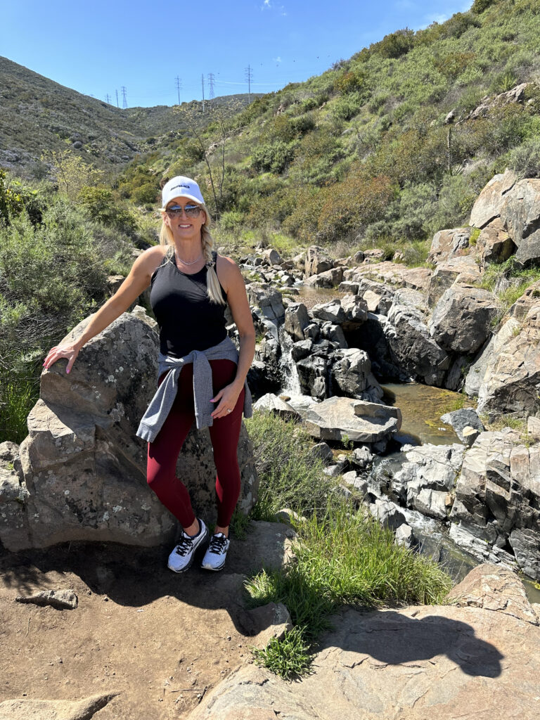 Kristi Jones smiling at the camera while standing next to a rock

The Kristi Jones Podcast- How Hiking, Getting Lost, and Encountering Rattlesnakes Helps Me Live Life to the Fullest