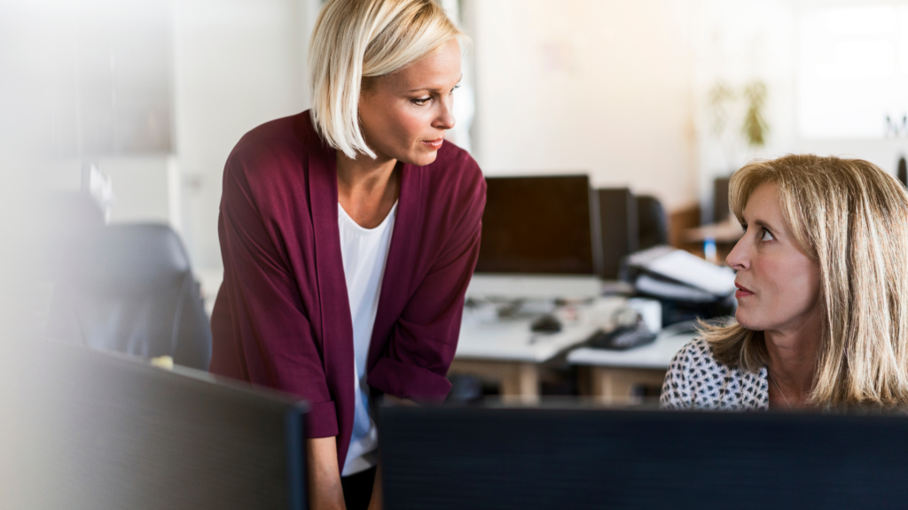 Two women talking in the office, Why Being Good Isn’t Enough Anymore Without Confidence - The Kristi Jones Show Podcast